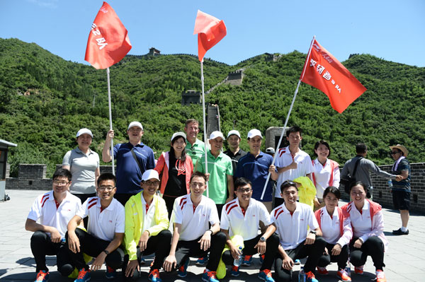 Li Ning, legendary gymnast and founder of Li Ning company, (middle in green) poses with company executives and 10 grassroots representatives at the launch of the Hiking The Great Wall mass fitness activity at Juyongguan Great Wall scenic spot, July 25, 2013. [Photo/China Daily]