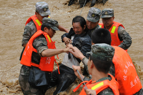 Soldiers with the 21st Group Army in the Lanzhou Military Area Command relocated about 600 residents affected by flooding in Niniangba township in Tianshui, Gansu province, on Saturday. CAO BAIMING / FOR CHINA DAILY