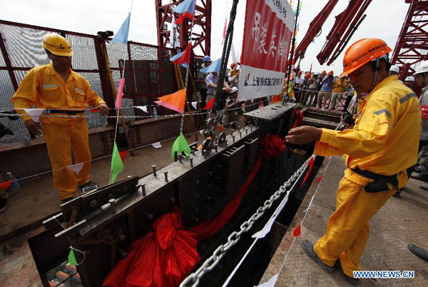 Two workers place the last beam on the main structure of the Shanghai Tower in Shanghai, east China, Aug. 3, 2013. A topping-out ceremony was held Saturday for the Shanghai Tower, China's tallest building, which remains under construction until its scheduled completion in 2015. The 125-story building, now 580 meters high, is scheduled to reach a final height of 632 meters upon completion in 2015. (Xinhua/Pei Xin)