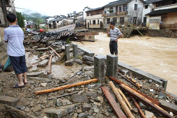 Huanxiu Bridge collapsed during a flash flood in June and most of it was swept away, leaving only parts of two piers. When the flood receded, villagers trekked miles along the river to salvage any parts they could find. [Photo By Zhang Jianping/For China Daily]