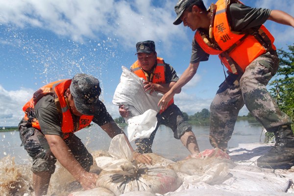 Soldiers stack bags of sand on Sunday after floodwaters in Heihe, Heilongjiang province, broke an embankment in the city's Beitaozi Island. Heihe is suffering its most severe flooding in 30 years. Wei Jianshun for China Daily