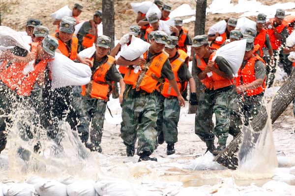 After more than five hours of work, soldiers successfully repaired a 1,000-meter dike that was on the verge of being breached in Xunke county, Heilongjiang province, on Saturday. The Heilong River's level in the county exceeded the danger mark by 1.76 meters on Saturday, causing the dike to spring several leaks. [Wei Jianshun / for China Daily]