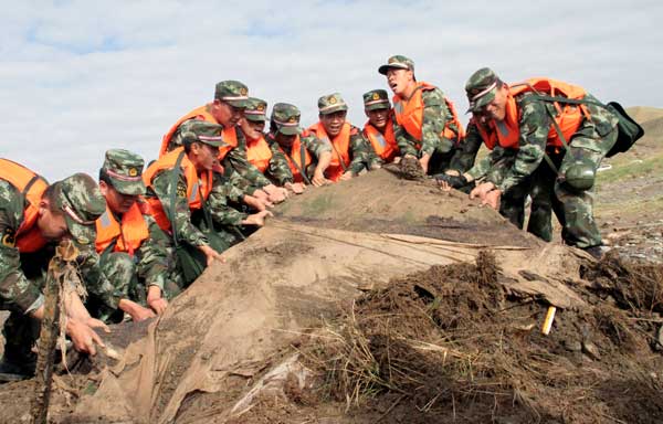 Government rescue workers help clean the debris left by a flood in Qinghai province on Wednesday. Rain and hail battered Wulan county in the Mongolian-Tibetan autonomous prefecture of Haixi on Tuesday, and authorities said on Wednesday that the death toll had reached 24. Yuan Zhiqi for China Daily