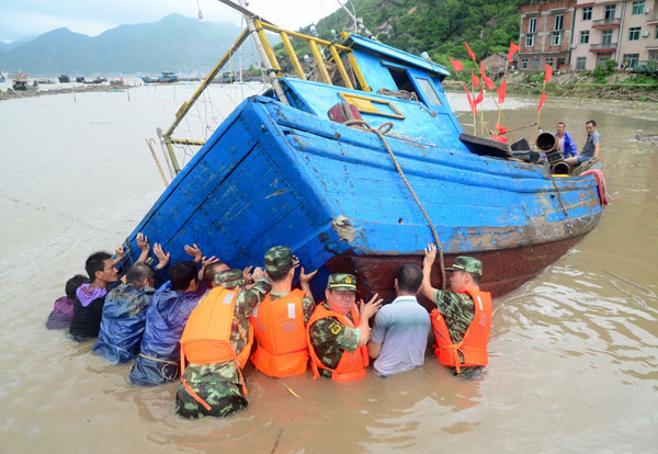 Troops and fishermen try to move a boat to a safer spot in Xiapu, Fujian province, on Thursday, after it was overturned by the powerful winds of Typhoon Trami. Yuan Ziyou for China Daily