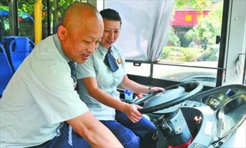 Dai Liqing (left) and wife Ren Yanli change shifts on bus route 719 in Wuhan, Hubei Province. Photo: Wuhan Evening News