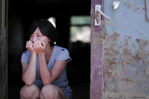 Li Yangyang sits in the doorway of her home, which was hit by floods on Aug 16, in Nankouqian village, Fushun, Liaoning province. She lost her grandmother in the flood, and her father was also swept away and is still missing. The death toll in the area has risen to 76, with 88 missing.Yao Jianfeng / Xinhua