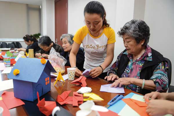 A social worker helps an elderly woman with some handicraft at a community center in Hangzhou, Zhejiang province. Xu Yu / Xinhua