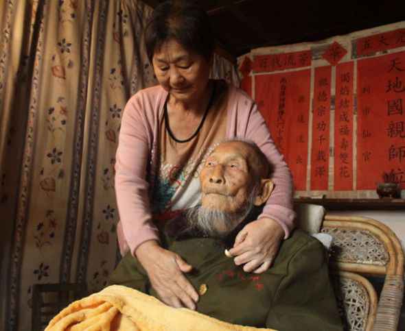 Fu Xinde, 112, the oldest survivor of the Chinese Expeditionary Force, is taken care of by his daughter-in-law in his home in Longling county, Yunnan province, on Monday. Hu Yongqi / China Daily