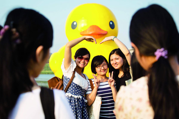 Tourists take pictures with the Rubber Duck, which landed in Beijing's Garden Expo on Sept 6. Mao Yanzheng / China Daily