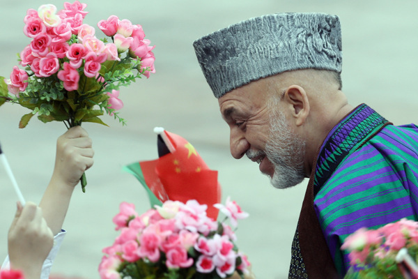 Afghan President Hamid Karzai smiles as children wave the national flags and flowers at a welcoming ceremony outside the Great Hall of the People in Beijing on Friday. Karzai was in Beijing for talks on bilateral cooperation with top Chinese leaders. Xu Jingxing / China Daily