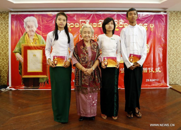 China's Myanmar-language professor Su Xiuyu (2nd L), who won one of the highest religious medals of commendation in honor of her excellent performances conferred by Myanmar President U Thein Sein, and Myanmar studends pose for group photos during the education stipend presentation ceremony in Yangon, Myanmar, Sept. 29, 2013. China's Myanmar-language professor Su Xiuyu provided stipends on Sunday for 27 outstanding Myanmar students from underprivileged families to pursue university education under the name of Professor Su-Xiuyu Fund. (Xinhua/U Aung) 