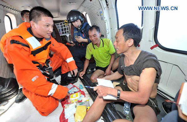 Rescuers talk with two fishermen after they were saved from the sinking ship Yuetaiyu 62116 in south China's Hainan Province, Oct. 1, 2013. As of 2 p.m. Tuesday, rescuers had retrieved 14 survivors. Two fishermen were confirmed dead while 58 others are still missing. Search is ongoing for 74 people missing in the South China Sea amid strong gales after three fishing boats have sunk since Sunday afternoon due to the Typhoon Wutip. (Xinhua/Zhao Yingquan)