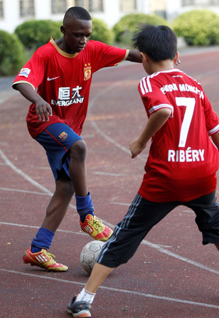 Ngolo Serge plays soccer with one of his Chinese teammates.