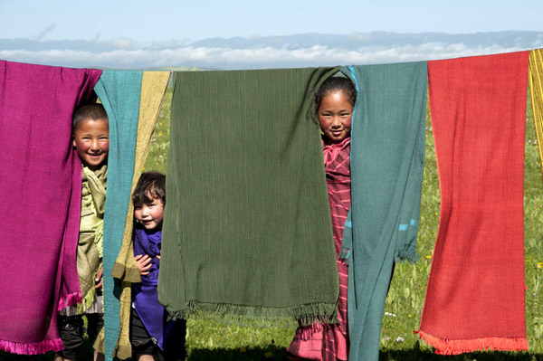 Tibetan children with shawls and scarves of the yak wool produced by Norlha.