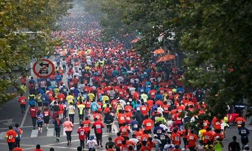 Usually packed with cars, marathon runners take over Huaihai Road Sunday. Photo: Cai Xianmin/GT