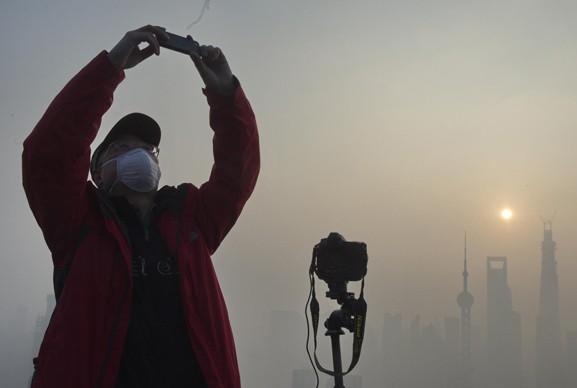 A resident in Shanghai takes a photo of the city's scenery amid heavy smog on Dec 7. [Photo/Xinhua] 