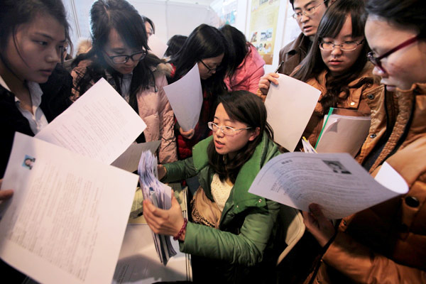 A recruiter is surrounded by employment seekers at a job fair for postgraduates in Beijing on Friday.[WANG JING / CHINA DAILY]