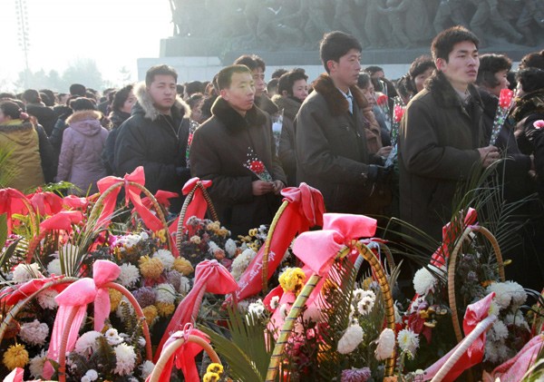 People offer flowers near bronze statues of the DPRK late founder Kim-il Sung and late leader Kim-jong Il at Mansudae in Pyongyang on Dec 16, 2013, on the eve of the second death anniversary of Kim-jong Il. [Photo / Xinhua]