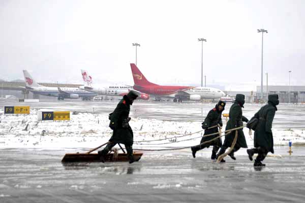 Soldiers of the Armed Police Force clear snow at Kunming Changshui International Airport in the capital of Yunnan province on Monday. It is rare to have snow in the city in Southwest China, known as the City of Spring for its pleasant climate. [Photo by He Yaxin / for China Daily]