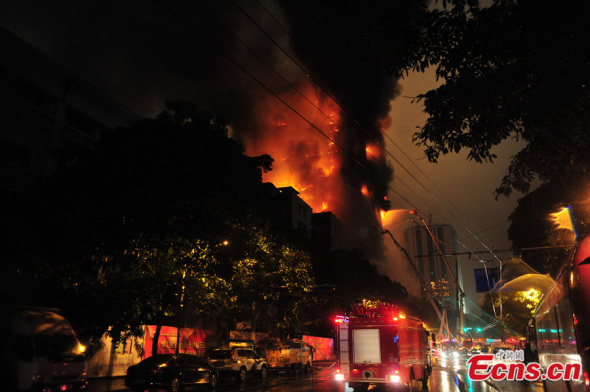 Fire was raging in a high-rise building in downtown Guangzhou, capital of south China's Guangdong Province, on the night of Dec 15, 2013. Several fire engines have arrived at the site trying to put out the blaze. [Photo: China News Service / Chen Jimin]