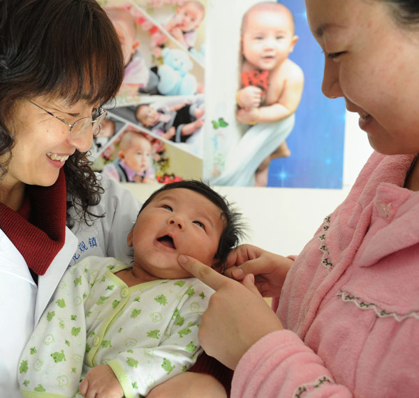 A doctor from the Huilongguan community health service center (left) examines a child. Beijing is planning to transform private hospitals and clinics into community health service center in an effort to provide better primary healthcare. Yan Tong / for China Daily