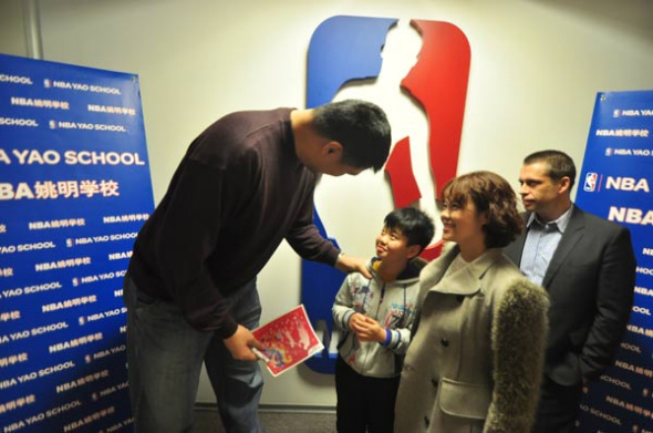 Yao awards a signed new year greeting card to a student after the event. [Photo by Sun Xiaochen / chinadaily.com.cn]