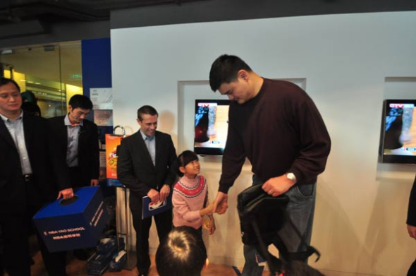 Yao shakes hands with a student, who won the lottery, at the event. [Photo by Sun Xiaochen / chinadaily.com.cn]