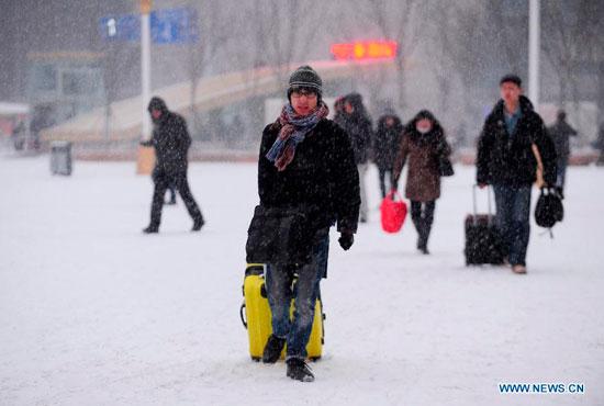 Passengers carrying luggages walk in the snow at the Shenyang North Railway Station in Shenyang, capital of northeast China's Liaoning province, Jan 19, 2014. Chinese people are rushing back home to spend the Spring Festival with family members. (Xinhua/Zhang Wenkui)