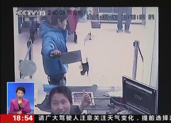 Surveillance video shows a knife-wielding man holding a cellphone walking around at a bank in Shanghai on Feb 20, 2014. (cctv.com)