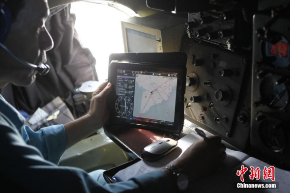 Photo taken on March 14 shows a pilot checks flight route during the search for the missing Malaysia Airlines flight MH370. (Photo/China News Service)