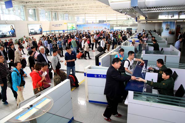 Outbound tourist groups wait to pass through a security checkpoint at Qingdao airport on Wednesday. Xie Hao / for China Daily 