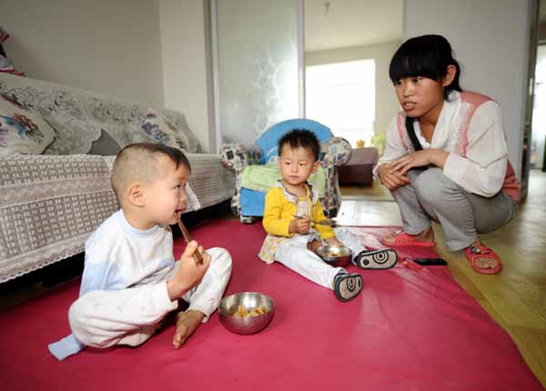 Xu Aixiang encourages her foster child, Wu Zhenfeng, to use his foot to hold chopsticks for dinner in their home in Taiyuan, Shanxi province. Wu was born without arms. Yan Yan / Xinhua