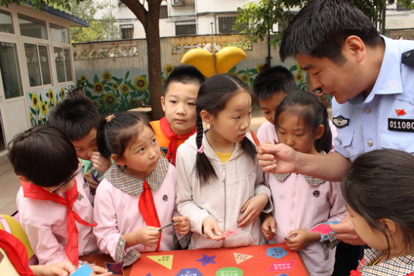 A police officer promotes pedestrian safety education by playing games with students at Beijing's Tiyuguan Road Elementary School on May 8.  Photo by Wang Kaihao/chinadaily.com.cn