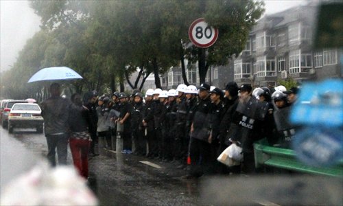 Police officers stand on alert at an entrance of Jiufeng village in Hangzhou, Zhejiang province on Sunday afternoon. Clashes broke out Saturday after thousands of protesters rallied against a planned garbage incinerator in the village. Photo: Yang Hui/GT