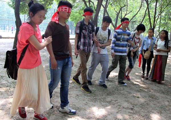 Volunteers cover their eyes to feel how blind people deal with walking. It is part of an event to mark the Day for Helping the Disabled, which was held in Beijing on Sunday. YAN XIAOQING / CHINA DAILY 