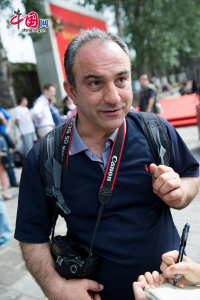 Beyhan Ozdemir, a photographer from Turkey, says his Beijing-related photos include that for a teahouse, restaurants, traditional Beijing drinks and shoe-making, at the opening ceremony of the 2014 Vision Beijing international photography event held at the Summer Palace in Beijing on Monday. [Photo by Chen Boyuan / China.org.cn].