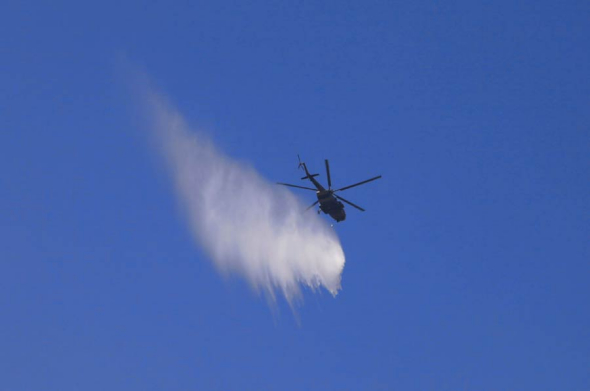 A helicopter helps to fight a forest fire in Weihai, Shandong province, May 30, 2014. [Photo/asianewsphoto]