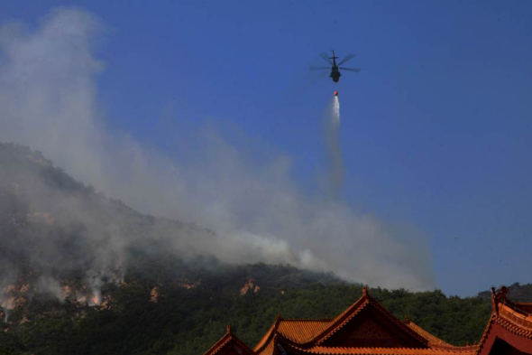 A helicopter is pressed into service to fight the forest fire in Weihai, Shandong province, May 30, 2014. [Photo/asianewsphoto]