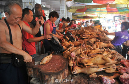 The undated photo shows a man is cutting dog meat at a stall in Yulin, Guangxi. [Photo: the official Sina Weibo account of People's Daily]