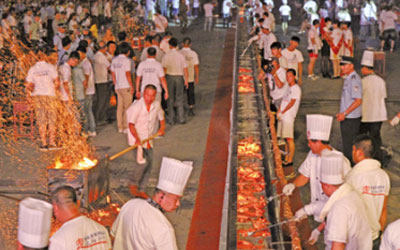 Chinese and Russian chefs cooking the 112-meter-long kebab at Suifenhe city on Wednesday, July 16, 2014. [Photo: xinhua]