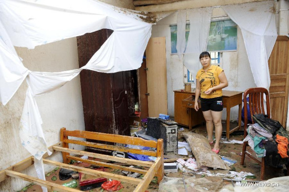Lin Yuanying stands in her house damaged by Typhoon Rammasun in Qianshan Township, Xuwen County, south China's Guangdong Province, July 19, 2014.  (Xinhua/Liang Xu) 