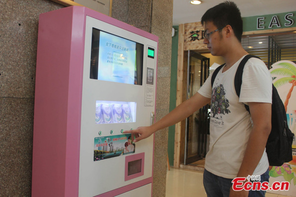 A man uses an ID-card-scanning vending machine to get free condoms at a shopping mall in Zhengzhou city of Henan province on July 24, 2014.