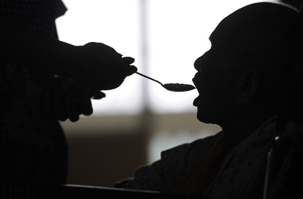 An employee at a nursing home in Zhongshan, Guangdong province, helps a patient with dementia eat in September 2013. Ye Zhiwen / for China Daily 