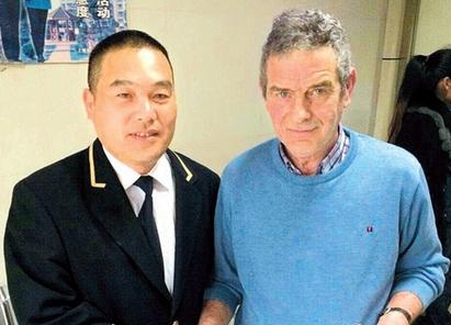 Liu Jun and Charles John McGirr shake hands after the Briton retrieved his belongings at Gaojing police station yesterday.  Guan Lu