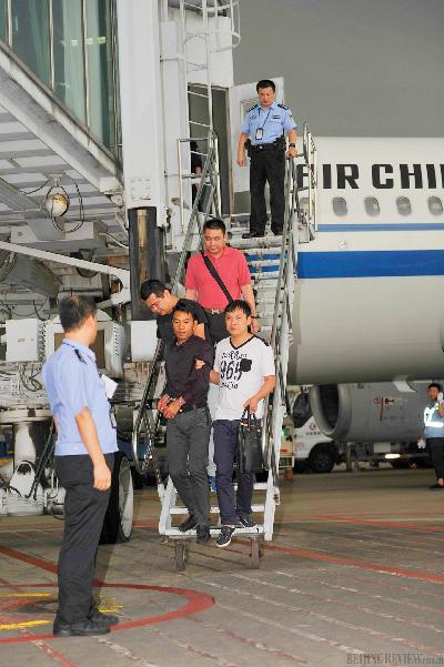 BROUGHT TO JUSTICE: Police officers escort a contract fraud suspect apprehended in Colombia from an airplane in Hangzhou, east China's Zhejiang province, on September 2 (CNSPHOTO)