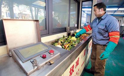 A worker puts kitchen wastes into a processing machine which converts them into fertilizer at the Yanji No. 7 community yesterday.  Wang Rongjiang