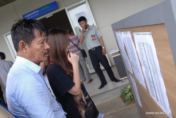 People related to passengers on AirAsia flight QZ8501 look on informations of the missing flight at Juanda International Airport in Surabaya, Indonesia, on Dec. 28, 2014. Rescuers searching for a missing AirAsia plane with 162 aboard over the Java Sea suspended their operation at nightfall on Sunday, Indonesia's transport ministry said. (Xinhua) 