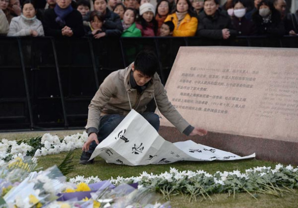 A young man places mourning couplets at Chen Yi Square in the Bund (below), site of the tragedy on New Year's Eve that claimed 36 lives. [Photo by Lai Xinxin/For China Daily] 