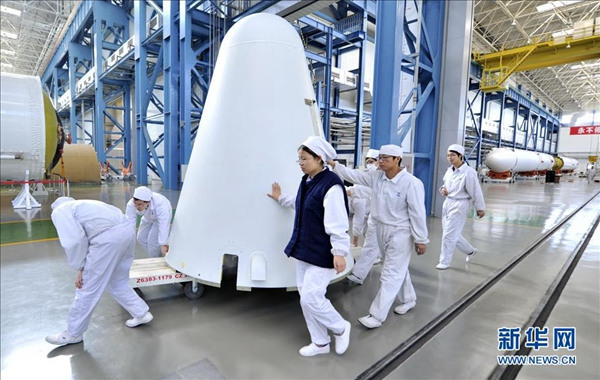 Photo taken on Dec 12, 2014 shows staff members transferred devices of Long March-7 Rocket. (Xinhua/ Yue Yue)