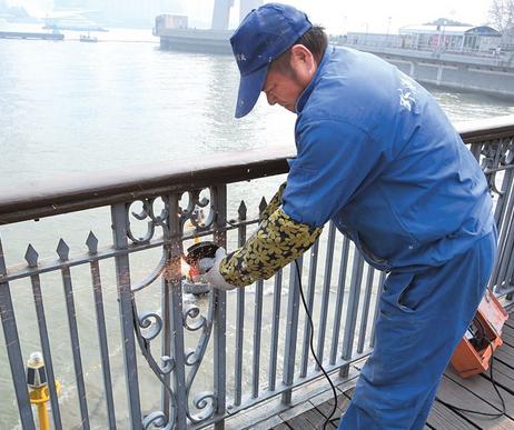 A worker breaks a love lock attached to the Waibaidu Bridge railings yesterday. A total of eight locks were removed from the bridge.  Wang Rongjiang